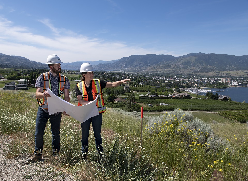 Two land surveyors reviewing plans in the field.