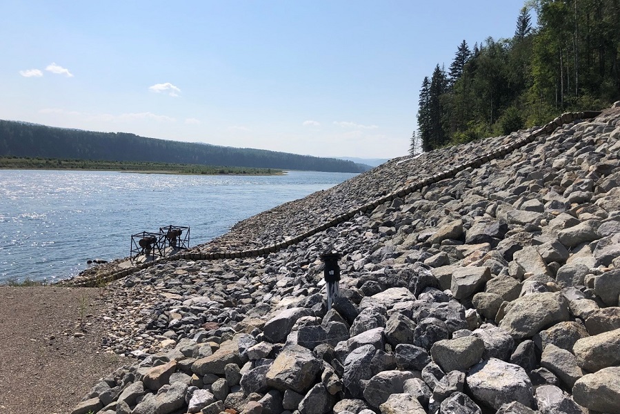 A waterline stretches from a body of water up gently sloped rocky shoreline