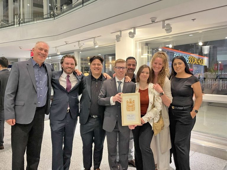 McElhanney team members celebrating together at the ACEC‑BC Awards Gala while holding an award recognizing engineering excellence.