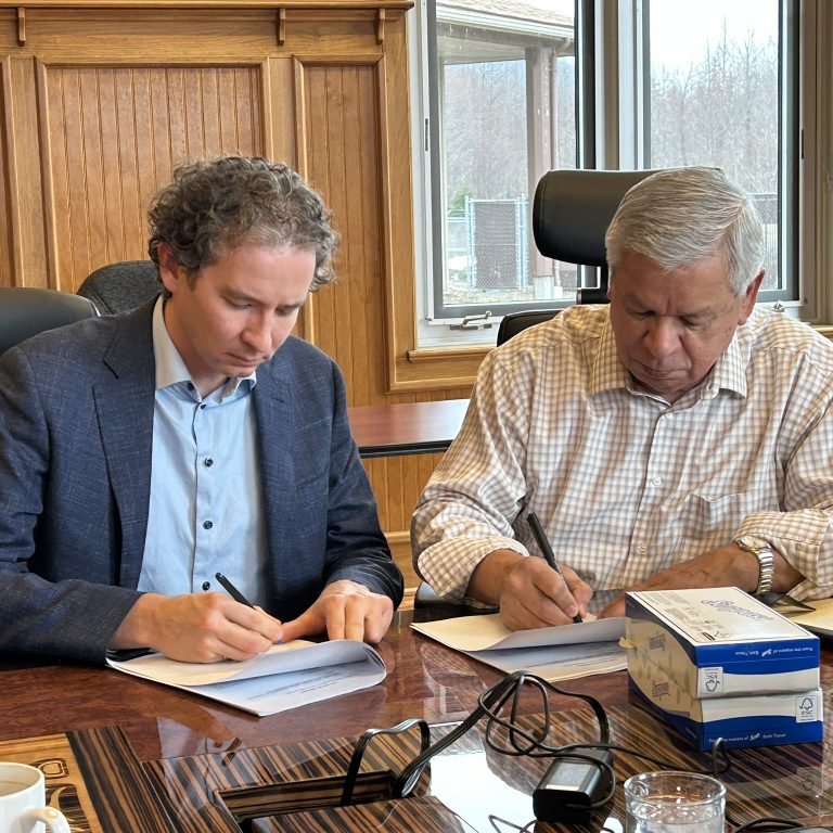 McElhanney Boney Creek Development Joint Venture Two individuals in a corporate board room signing paper documents with pens.