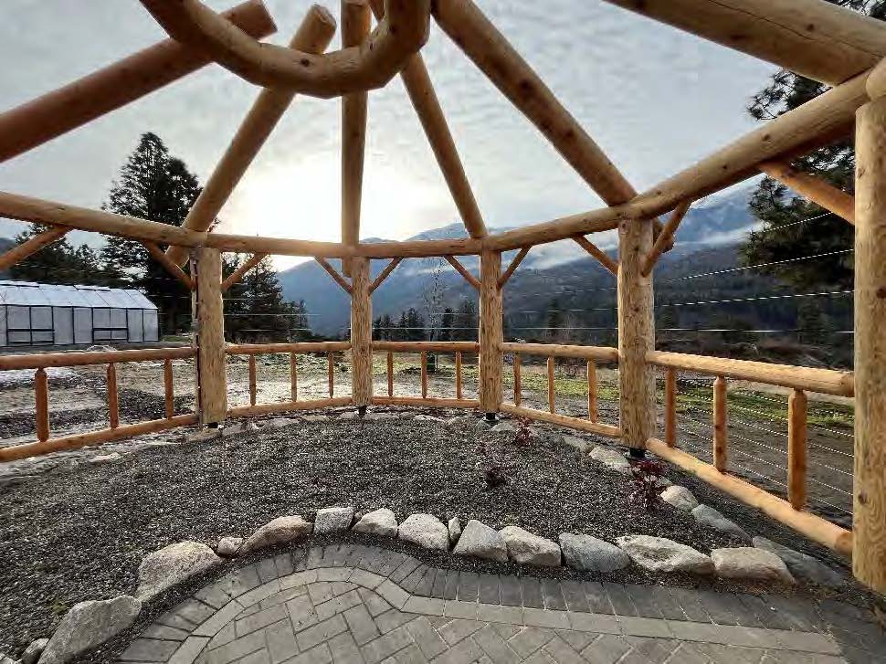 View through an open-air timber frame gazebo-style structure to a mountain horizon line.