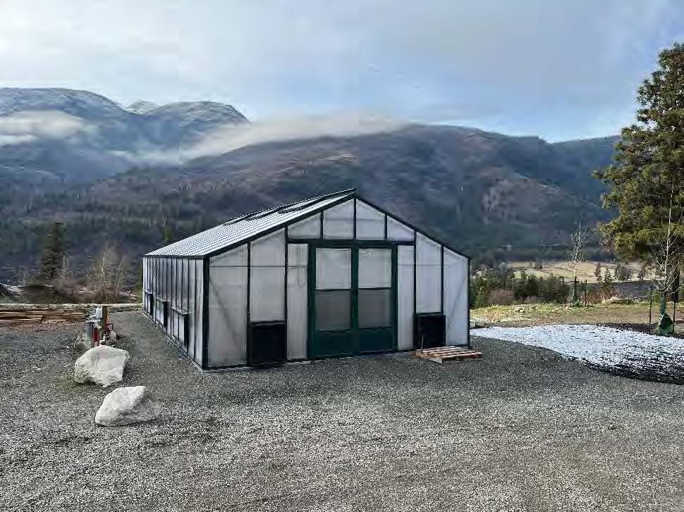 View of a greenhouse in the foreground. Mountains are visible in the background.