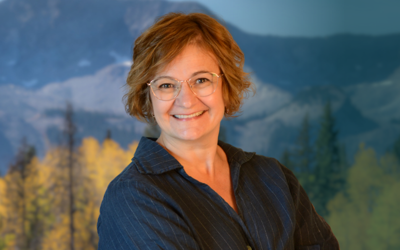 Senior McElhanney strategic program leader pictured outdoors with a mountain landscape in the background.