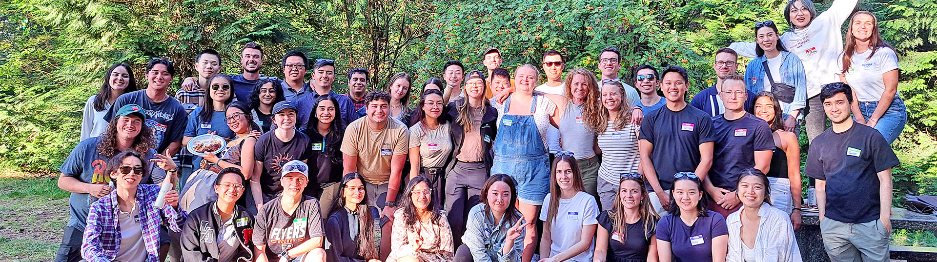 Career Opportunities Banner A diverse group of McElhanney team members gathered outdoors among trees during a team event.