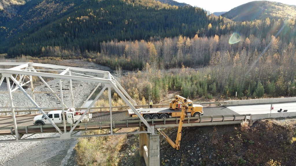 Inspection equipment positioned on a steel truss bridge crossing a river valley during structural evaluation and asset management work in a mountainous transportation corridor.