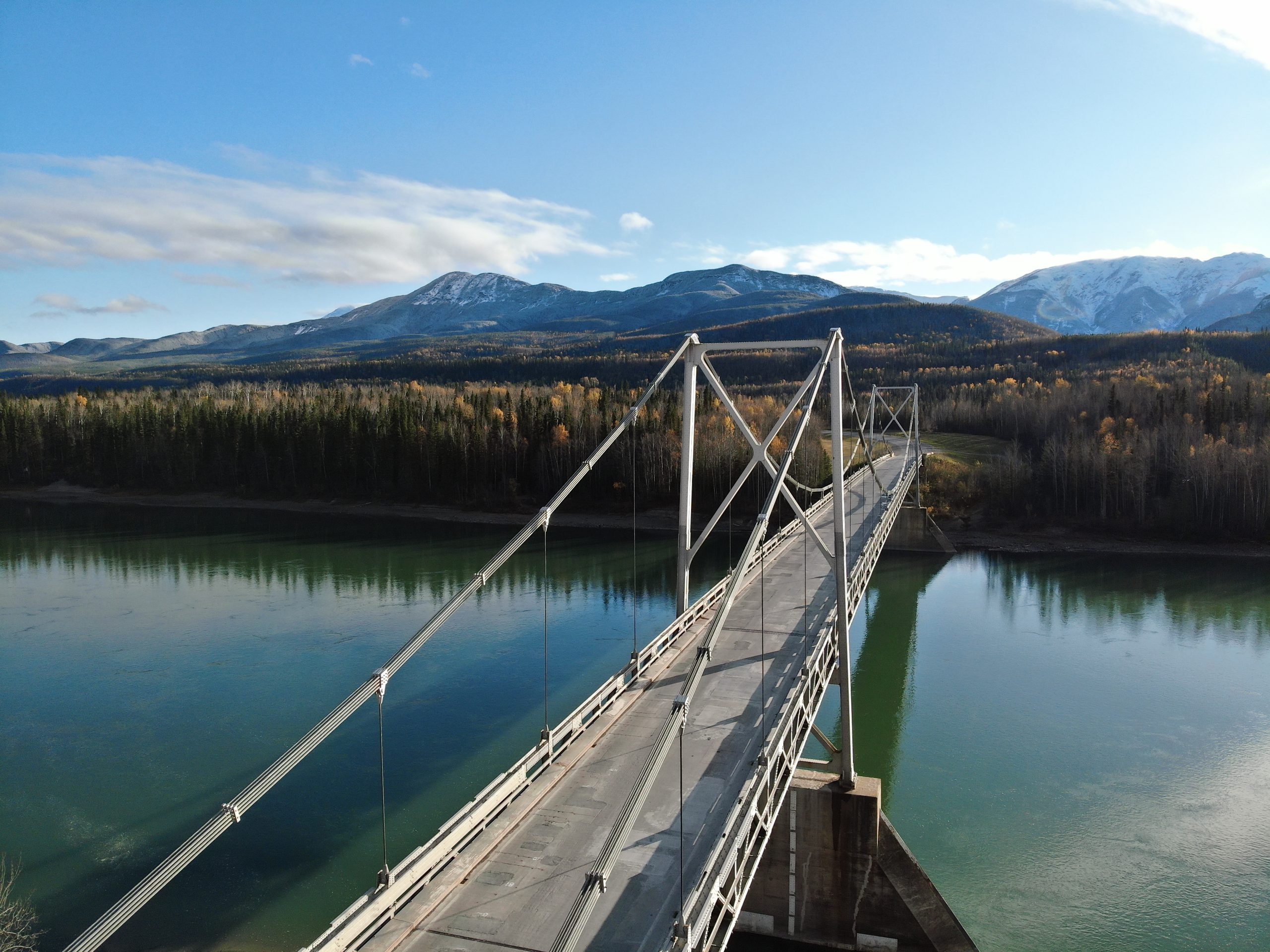 Bridge Evaluation and Inspection Services on the Alaska Highway Suspension bridge spanning a river in northern British Columbia with mountain views, inspected as part of the Alaska Highway structural evaluation and testing program.