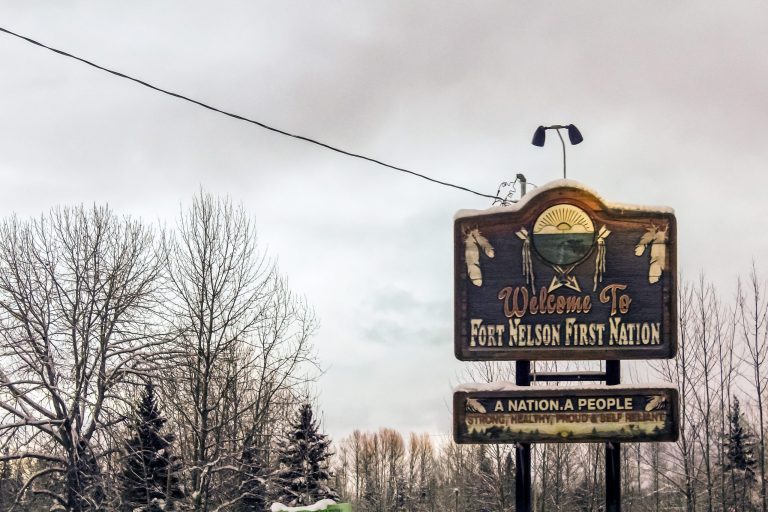 Welcome to Fort Nelson First Nation Sign reading “Welcome to Fort Nelson First Nation” with trees and sky in the background.