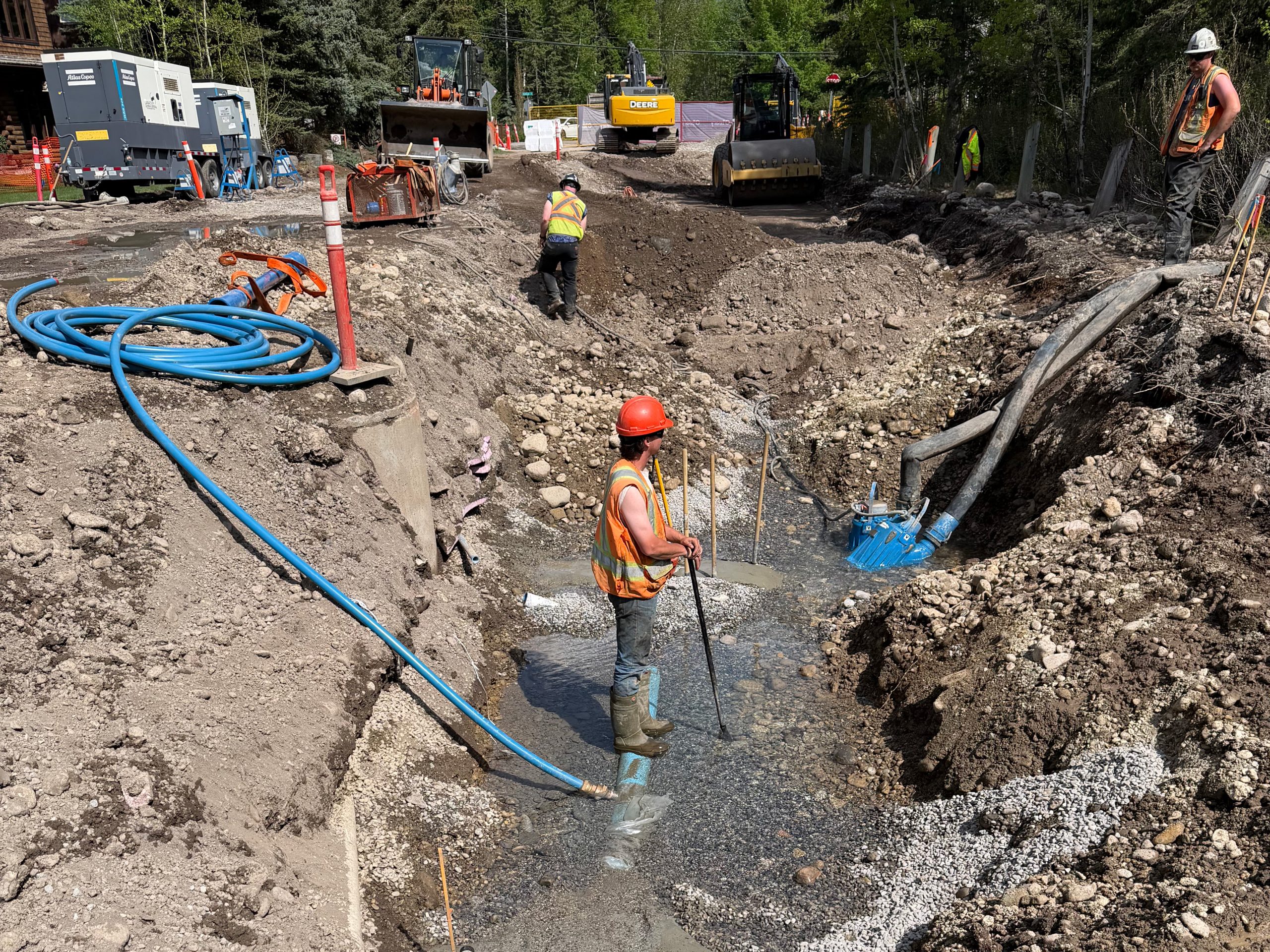 South Canmore infrastructure upgrades Workers and excavation equipment installing deep utilities along residential street trench in South Canmore infrastructure upgrade project