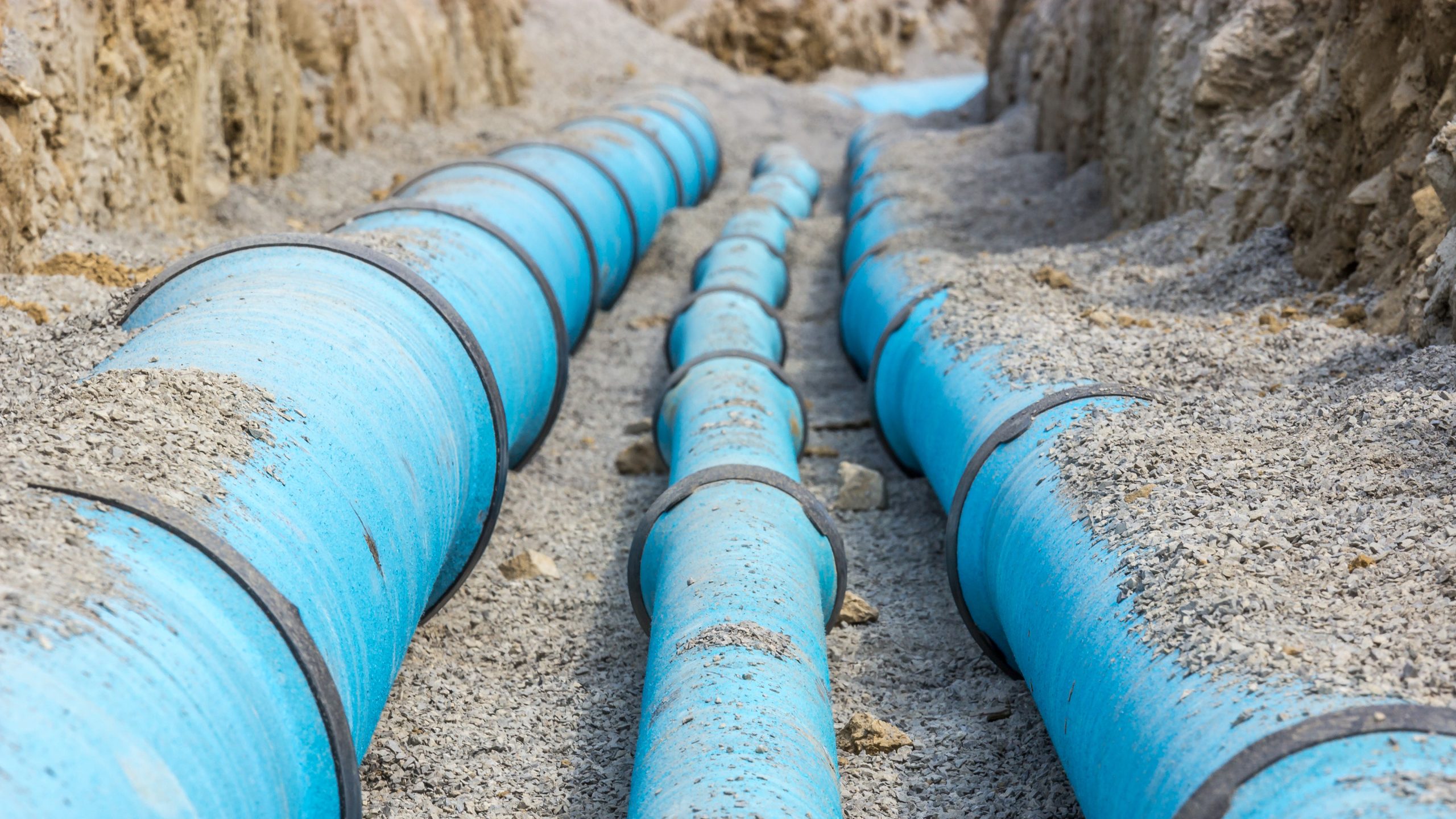 Watermain infrastructure Large watermain pipes installed in an excavated utility trench.